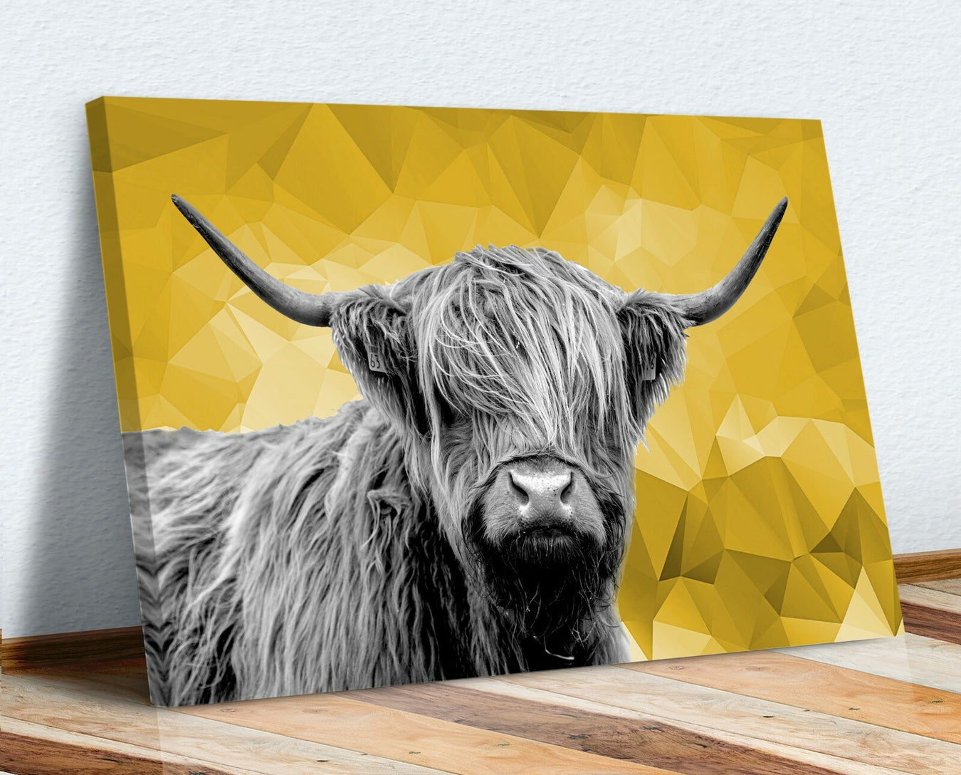 Canvas print of a highland cow with a yellow geometric background on a wooden surface.
