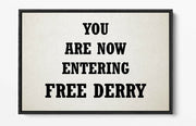 Framed sign with text 'YOU ARE NOW ENTERING FREE DERRY' on a plain background