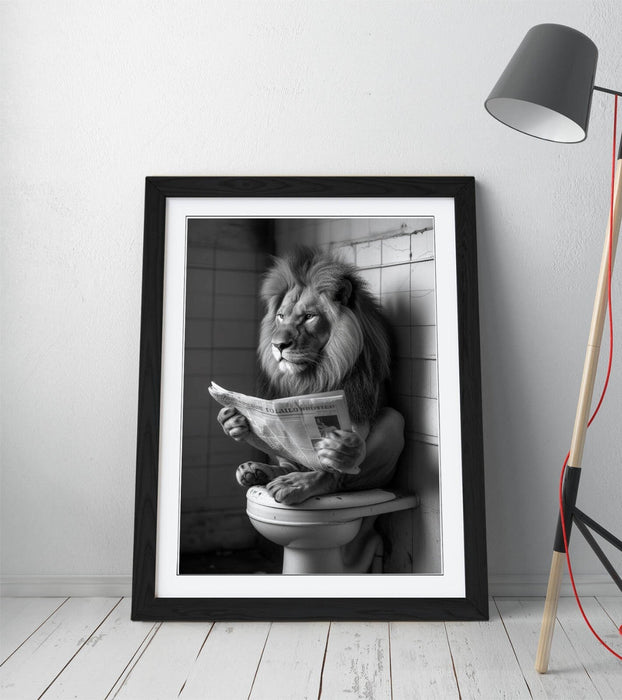 Framed black and white print of a lion reading a newspaper on a toilet, leaning against a tiled wall.